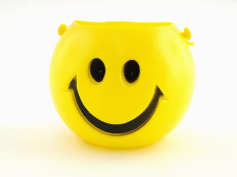 A plastic yellow smiley face bucket isolated on a white background.