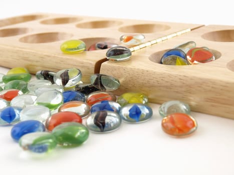 A folding wooden Mancala board game with glass stone pieces, isolated against a white background.