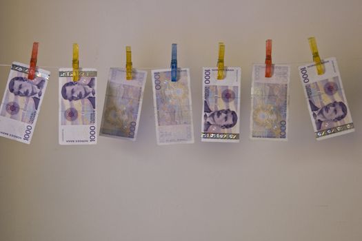 Illustration with the highest denomination of bank notes in Norway, hanging on a clothes hanger with clothes-pegs. Could illustrate money laundering and illegal business, but also a good illustration for wealth and money. 