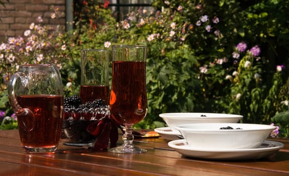 Living in the garden in summer - table with fresh picked blackberries, drinks and yogurt