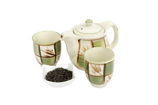 A porcelain tea set comprising one decorated teapot, two decorated teacups and a container holding shredded tea leaves on white background. Clipping path included.