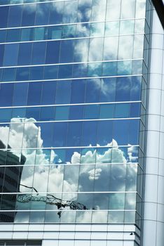Blue sky and white clouds reflected in a modern building's glass panels
