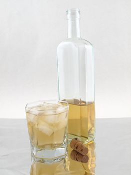 A glass and bottle of alcohol isolated on a reflective background