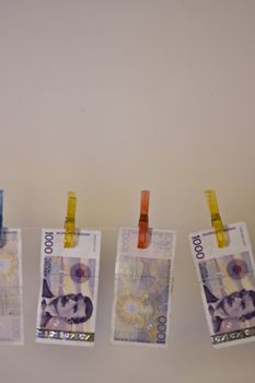 Illustration with the highest denomination of bank notes in Norway, hanging on a clothes hanger with clothes-pegs. Could illustrate money laundering and illegal business, but also a good illustration for wealth and money. Space for printing / design over the money.