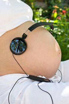 Headphones on a pregnant woman's stomach
