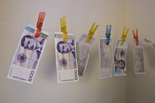 Illustration with the highest denomination of bank notes in Norway, hanging on a clothes hanger with clothes-pegs. Could illustrate money laundering and illegal business, but also a good illustration for wealth and money.