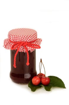 Cherry jam in a glass with fresh cherries on bright background