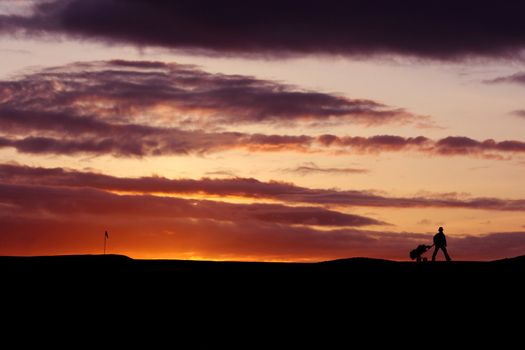 Golfer playing into the sunset walking off to the next hole