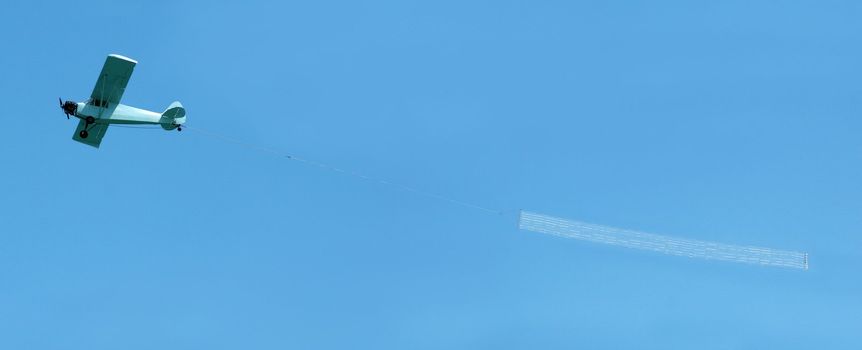 Small airplane towing a blank banner through the air - insert your own message