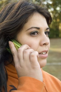 A beautiful young woman of latin descent talking on a cell phone