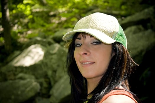 A girl dressed in summer clothes posing out in the woods.