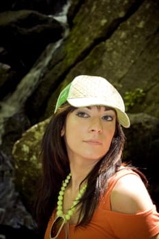 A girl dressed in summer clothes posing in front of a nice waterfall in the woods.    Plenty of copy space.