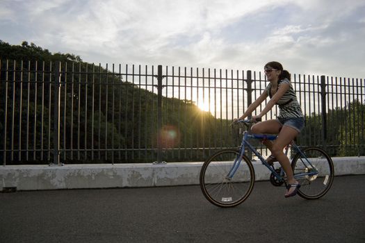 A young woman riding a bicycle across the bridge.