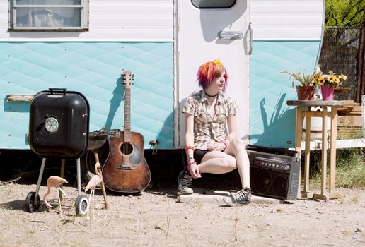 Punk girl with brightly colored hair sitting on a trailer step