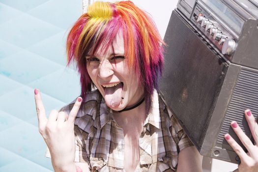 Punk girl with brightly colored hair sitting on trailer step holding boom box