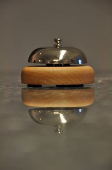 Detail shot of a service bell located on a hotel reception desk with great reflection on marble counter