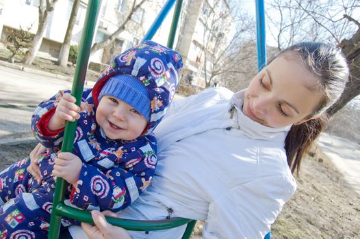 Happy baby boy and his mother on swing