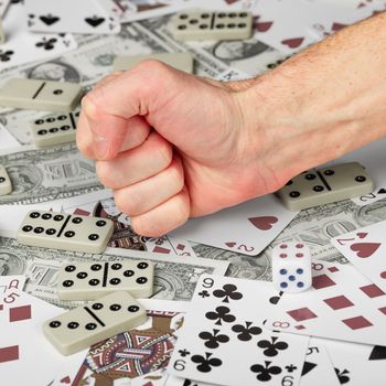 The hand clenched in a fist against the background of cards and money.