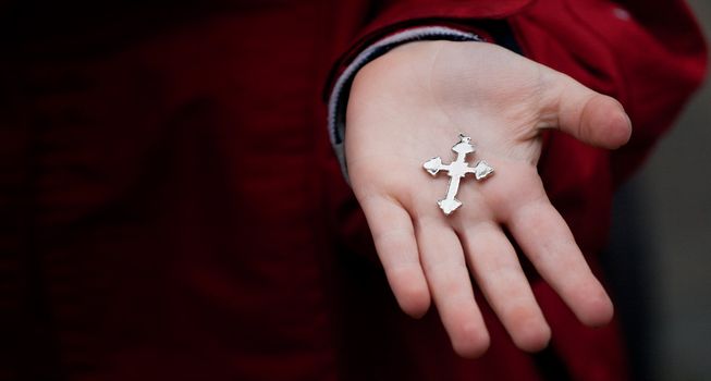 Small metalic crucifix in child palm