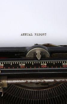 Close up of an antique typewriter with the words Annual report written on the paper - main focus on letters