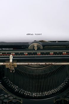 Close up of an antique typewriter with the words Annual report written on the paper - main focus on letters