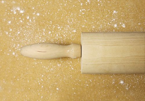 Close-up of a wooden rolling pin on flattened dough