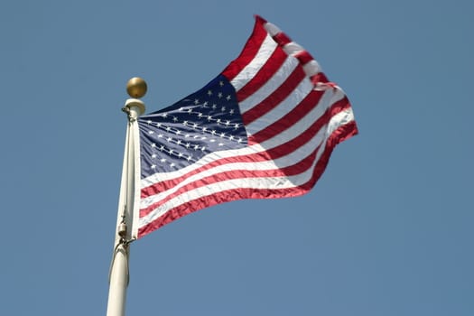 Waving USA american flag on blue sky background.