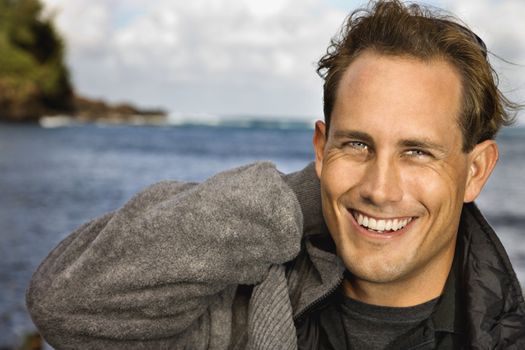 Caucasion mid-adult man looking at viewer, smiling, by ocean in Maui, Hawaii.