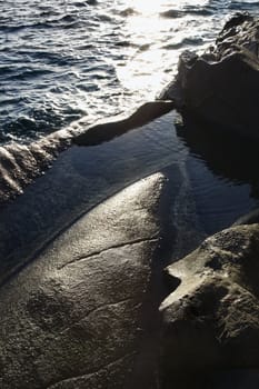 Big rocks on coast with lapping water.