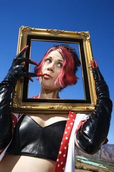 Young adult Caucasian female holding empty frame around head.