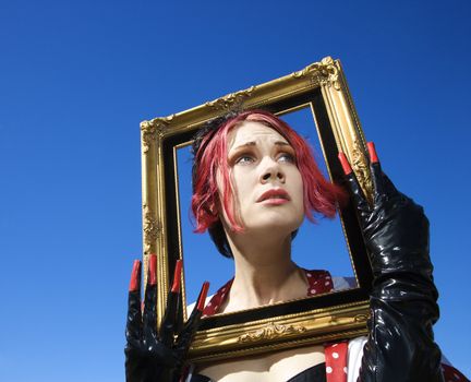 Young adult Caucasian female holding empty frame around head.