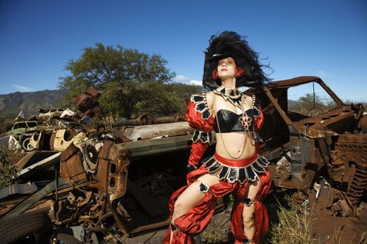 Young adult Caucasian female dressed in pirate costume in junkyard.