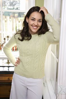 Caucasian/Hispanic young woman smiling with hand on hip looking at viewer.
