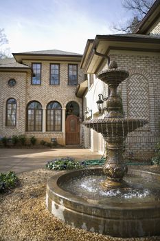 Outdoor front view of affluent home with fountain.