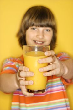 Portrait of Caucasian boy holding out glass of orange juice.