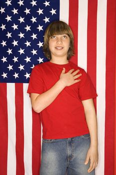 Portrait of Caucasian boy with hand over heart with american flag background.