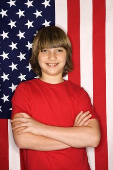 Portait of Caucasian boy with arms crossed with American flag in background.