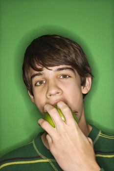 Portrait of Caucasian teen boy biting apple.