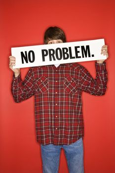 Portrait of Caucasian teen boy holding no problem sign under his eyes.