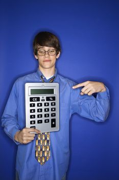 Portrait of Caucasian teen boy holding and pointing to oversized calculator.