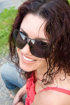 Young woman wearing sunglasses, with a wide smile.