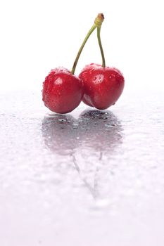 Two cherries, with water droplets, with reflection. Portrait framing.