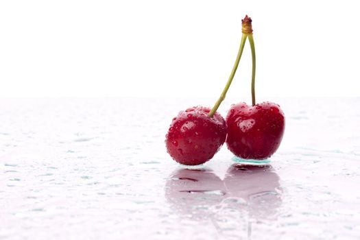 Two cherries, with water droplets, with reflection. Landscape framing.