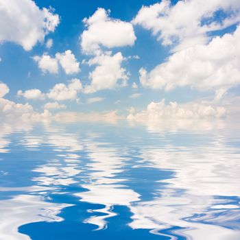 Blue sky with fluffy clouds reflected on water surface.