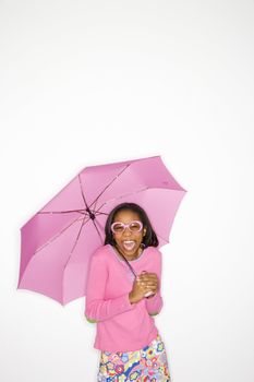 Portrait of African-American teen girl holding a pink umbrella standing in front of white background.