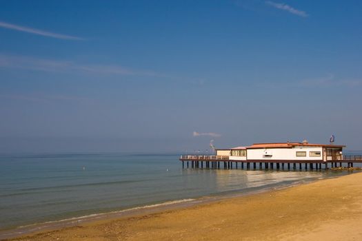 A view over the mediterranean sea, with a white house on an Italian beach