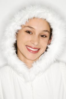 Portrait of Asian-American teen girl wearing fur lined coat hood and smiling against white background.