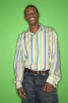 Portrait of smiling African-American teen boy standing in front of green background.