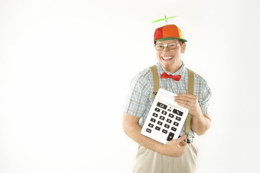 Caucasian young man dressed like nerd wearing beanie and smiling while holding large calculator.