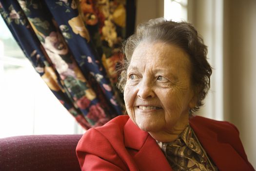 Elderly Caucasian woman by window at retirement community center.